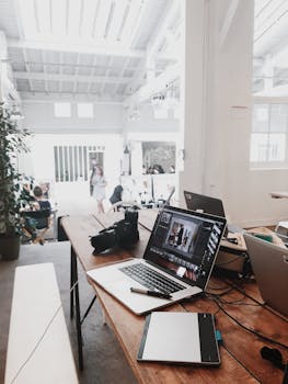 pexels photo 699459 699459 1 A bright, modern workspace featuring laptops, a camera, and a drawing tablet in an indoor office.